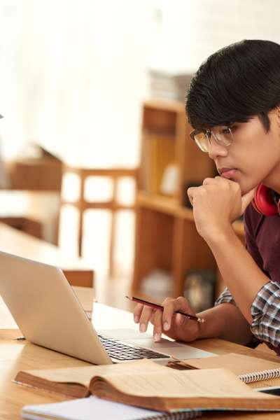Pensive university student reading something on laptop screen